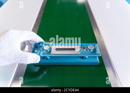 Close up of hand Mechanic technician worker use a water level meter working and Assemble the product sorting machine conveyer in industrial factory. Stock Photo