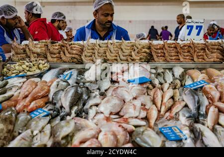 ABU DHABI, UAE, MAR 22, 2018: Man prepares fish for sale at the largest fish market in Abu Dhabi Stock Photo