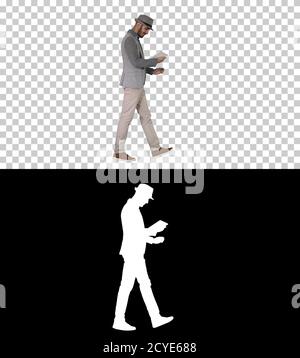Casual man using tablet and smiling while waking, Alpha Channel Stock Photo
