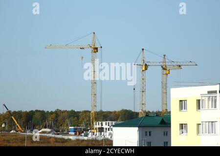 New complex of apartment buildings under construction with yellow cranes in the fields of a countryside. Crane and building construction site Stock Photo