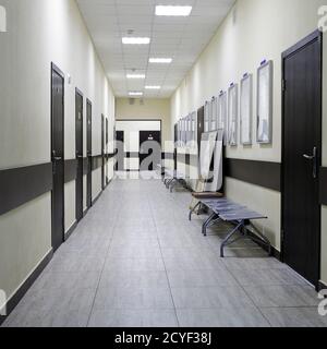 empty corridor in the modern office building. There are many brown doors along a very long corridor with beige walls. Stock Photo