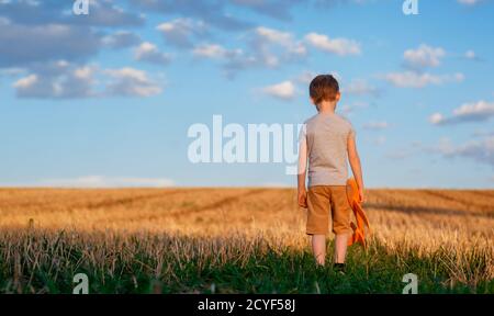 Happy child running with toy airplane on sky background happy family Concept. Childhood dream Stock Photo