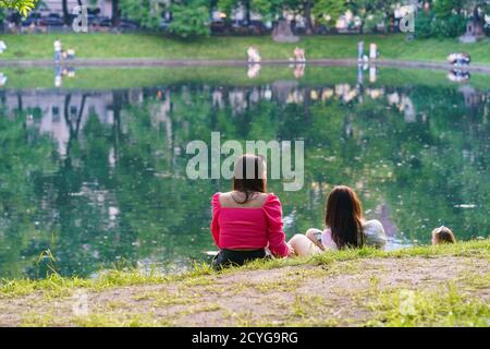 Moscow street life in summer hot day. Coronavirus quarantine is over. People go for a walk. They are sitting near the Patriarch Ponds in Moscow city c Stock Photo