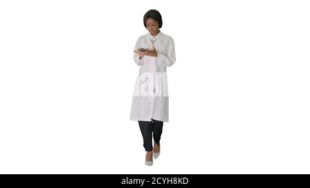 African American female doctor using phone while walking on whit Stock Photo