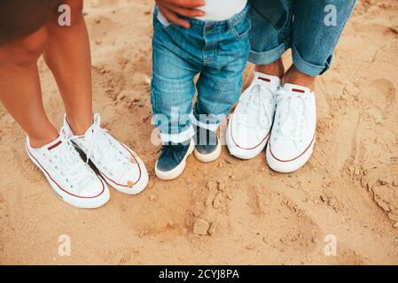 Beautiful photo of three pairs of shoes mom, dad and baby son on beach. Stock Photo