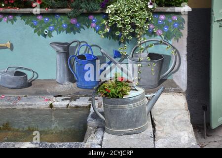 Vintage or Old Metal Watering Can & Painted Watering Cans Decorating Village Fountain or Street Fountain Colmars-les-Alpes Provence France Stock Photo