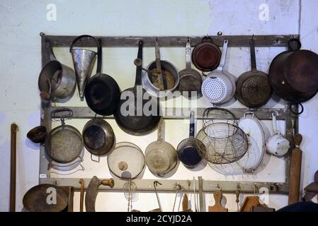Display in Old Kitchen of Antique or Vintage Pots & Pans Hanging on Wall Stock Photo