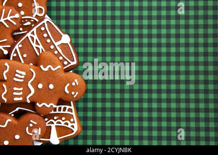 Tasty homemade Christmas gingerbread cookie of various shapes with sugar glaze on a green checkered background with copy space. Merry Christmas card Stock Photo