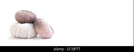 Three balls of beautiful, delicate yarn and knitting needles on a bright background. Banner. Craft on white background. Knitwear as a concept Stock Photo