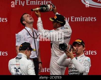 Mercedes driver Lewis Hamilton (2nd R) pours champagne after winning the Canadian F1 Grand Prix ahead of team mate Nico Rosberg and Williams driver Valtteri Bottas (L) at the Circuit Gilles Villeneuve in Montreal June 7, 2015.  Formula One world champion Lewis Hamilton won the Canadian Grand Prix on Sunday in a Mercedes one-two with title rival Nico Rosberg.The Briton's fourth victory in seven races this season, and fourth career win in Canada, stretched his lead over Rosberg to 17 points and denied the German a third win in a row.  REUTERS/Chris Wattie   TPX IMAGES OF THE DAY