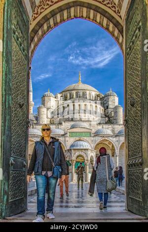 Istanbul, Turkey - April 1, 2016 - Woman walks out through doors of the Blue Mosque Stock Photo