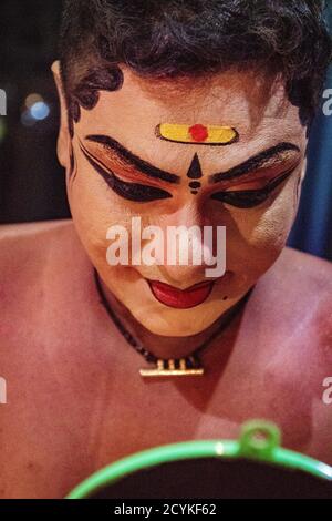 Munnar, India, Mar 11, 2018 - Traditional Indian dancer applies paint to his face prior to show Stock Photo