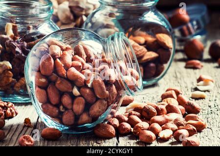 Raw peanuts in a glass jar on the vintage wooden table, selective focus Stock Photo