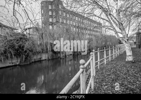 A black and white photo of the view down the riverside footpath along the River Wensum in the city of Norwich, Norfolk. This peaceful and tranquil path along the river is the ideal place to get away from the hum drum of city life. Stock Photo