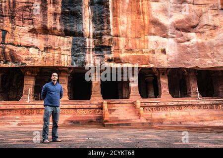 man standing at ancient rock cut cave in the morning image is taken at badami karnataka india. it is unesco heritage site and place of amazing chaluky Stock Photo