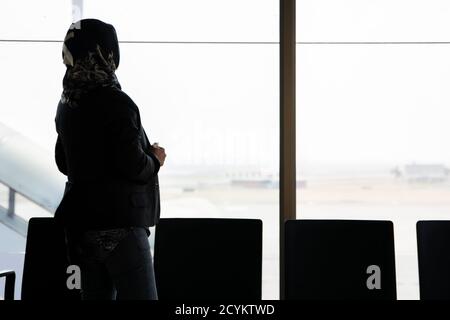 the silhouette of the rear view of a veiled Muslim woman standing in ...