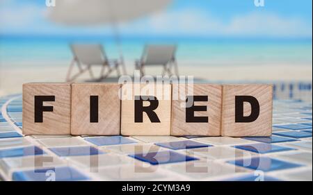 Wooden cubes with word Fired on mosaic border of swimming pool. Cubes with blue letters. Career and business concept Stock Photo