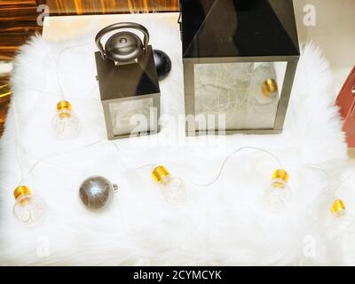 Two decorative lanterns with a garland and a Christmas tree ball on a white fur mat Stock Photo