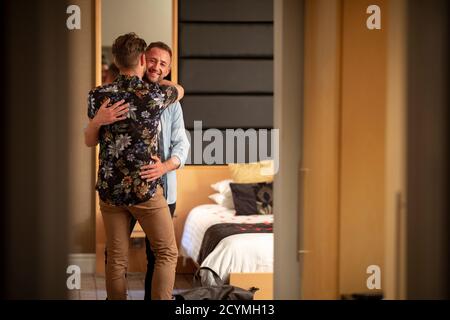 Two caucasian men embracing in a hotel room, they have a romantic evening planned. Stock Photo