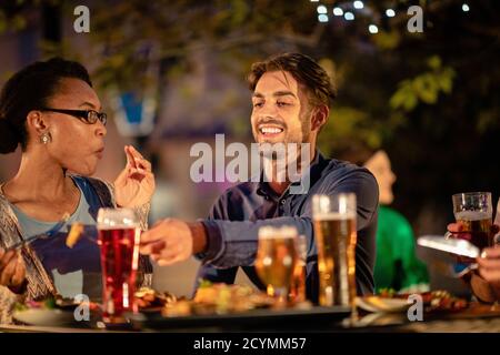 Friends drinking Alcohol outdoors at a bar/restaurant, celebrating and having fun together. Stock Photo