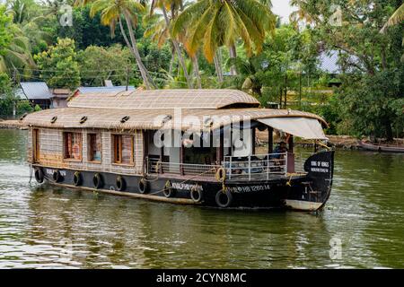 ALLEPPEY, INDIA, MAR 13, 2018: Bamboo thatched houseboat floats down the backwaters of Kerala Stock Photo