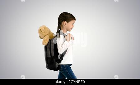 Cute little girl walking to school with a teddy bear sticking ou Stock Photo