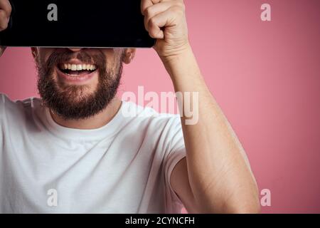 Man advertises a tablet on a pink background codes Space cropped view of emotions white t-shirt model new technologies Stock Photo