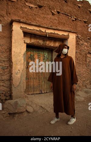 Moroccan Man in Traditional Djellaba Standing at an Ancient Kasbah Door Stock Photo