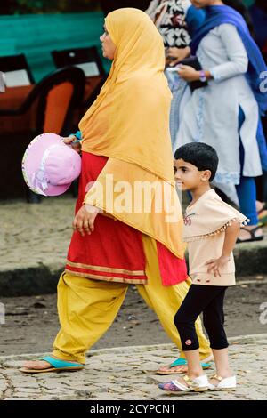 Woman in colourful traditional dress and hijab and young girl in modern clothes on the waterfront of Fort Cochin; Fort Cochin, Kochi, Kerala, India Stock Photo