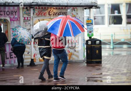 Brighton UK 2nd October 2020 - Staying dry under a Union Jack umbrella on Brighton seafront as Storm Alex sweeps across Britain bringing strong winds and rain especially in southern areas  : Credit Simon Dack / Alamy Live News Stock Photo