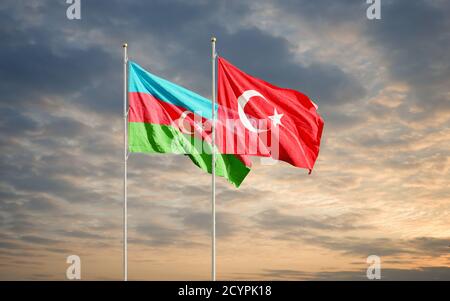 Azerbaijan and Turkey flags waving in the dawn sky. Symbol of international agreement and support during Karabakh war conflict with Armenia. Stock Photo