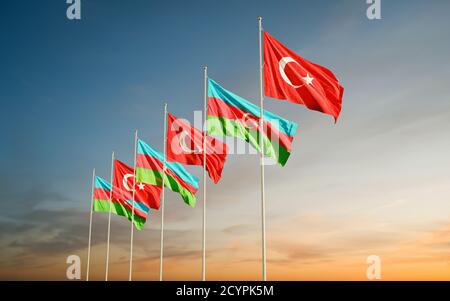 Azerbaijan and Turkey flags waving in the sunrise sky. Symbol of international agreement and support during Karabakh war conflict with Armenia. Stock Photo