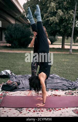 Vertical shot of a Caucasian woman doing gymnastic poses in the park Stock Photo