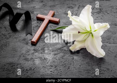 White lily with cross and black ribbon. Funeral concept Stock Photo