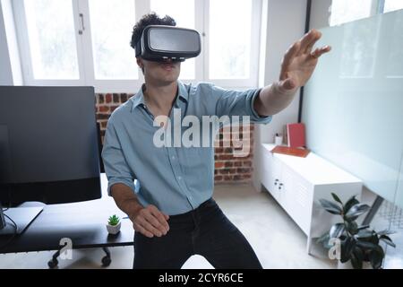 Caucasian man working in a casual office, wearing vr headset, touching virtual screen. Social distancing in the workplace during Coronavirus Covid 19 Stock Photo