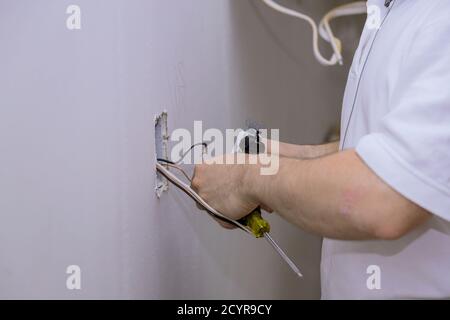 Construction in closeup of electricians hand installing outlet on wall with using professional tools. Stock Photo
