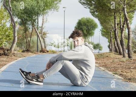 Young Caucasian man sitting on the street Stock Photo