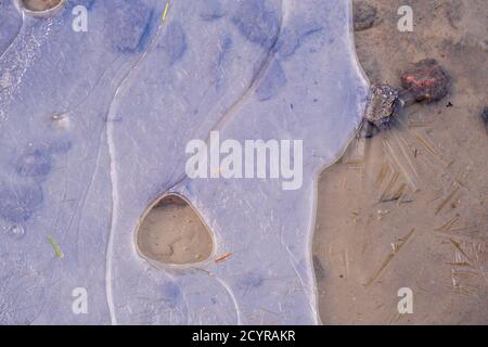 Frozen ice at a sandy beach Stock Photo