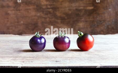 Unusual blue tomatoes in different stages of ripening on a wooden background Stock Photo