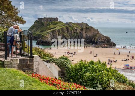 Two tourists enjoying the view of Tenby South Beach and St Catherine's Island in the summer,  Pembrokeshire Coast National Park,  Pembrokeshire, Wales