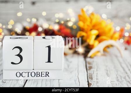 Halloween Day. White wood calendar blocks with the date October 31st and autumn decorations over a wooden table. Selective focus with blurred backgrou Stock Photo