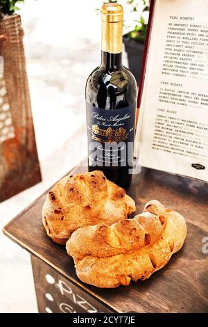 05.06.2018 - A loaf of traditional bread and a bottle of local wine displayed in front of a restaurant along with the menu in Matera, Italy as a sign Stock Photo