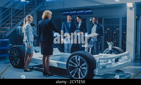 International Team of Automobile Design Engineers Introducing Futuristic Autonomous Electric Car Platform Chassis to Group of Investors and Stock Photo
