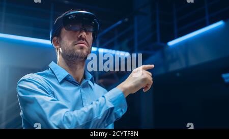 In 3D Content Creating Laboratory Engineer Wearing Professional Virtual Reality Headset Works and Gestures in Augmented Reality. Stylish Low Angle Stock Photo