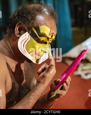 Munnar, India, Mar 11, 2018 - Traditional Indian dancer applies paint to his face prior to show Stock Photo