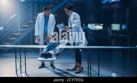 Meeting of Aerospace Engineers Working On Unmanned Aerial Vehicle Drone Prototype. Aviation Scientists in White Coats Talking. Commercial Aerial Stock Photo