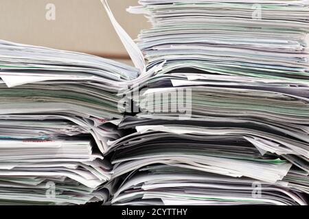 Office paperwork stacked haphazardly on a desk, closeup image. Overworked concept in business environment. Stock Photo