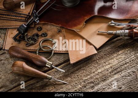 Leather craft tools on old wood table. Leather craft workshop. Stock Photo