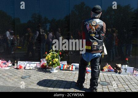 A motorcycle rider views the names of the thousands of fallen military on the Vietnam Veterans Memorial, along with flowers, remembrances and keepsakes left by visitors, as he joins hundreds of thousands of motorcycle riders on Memorial Day weekend for the 26th Annual Rolling Thunder Rally to remember POWs and MIAs from America's wars, in Washington, May 26, 2013.   REUTERS/Mike Theiler   (UNITED STATES - Tags: SOCIETY ANNIVERSARY)