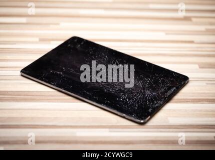 Broken tablet computer lying on a floor with cracked touch screen Stock Photo